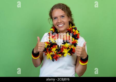 Feliz rubia mujer fan de fútbol de Alemania aislado en verde antecedentes Foto de stock