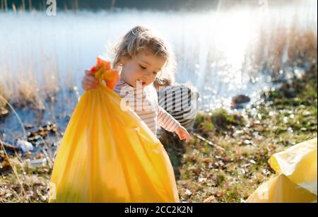 Niños pequeños recogiendo basura al aire libre en la naturaleza, el concepto de empañamiento.