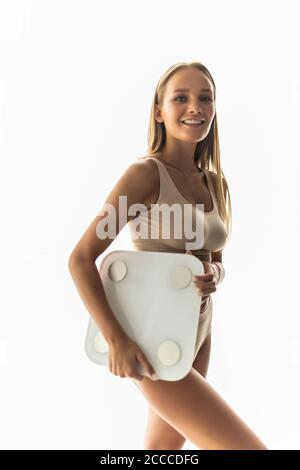 Mujer joven midiendo el peso corporal sobre la báscula en casa Foto de stock