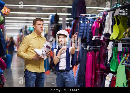 vamos a ver este, pareja en la tienda de ropa deportiva, mujer en casco  protector mostrar en otro equipo en surtido, con el marido Fotografía de  stock - Alamy