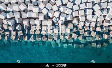 Vista aérea de un joven sobre bloques de cemento que protegen la costa de las olas del puerto de Málaga, España. Foto de stock