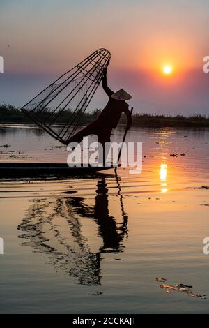 Myanmar, estado de Shan, Silhouette del pescador tradicional de Intha en el lago de Inle al atardecer Foto de stock