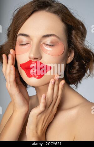 Mujer que usa una máscara labial de colágeno y parches bajo el ojo Foto de stock