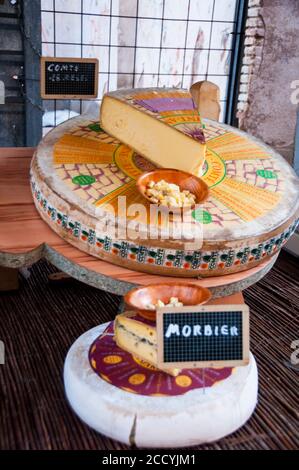 Ruedas artesanas de queso de leche de vaca francesa Comté y Morbier en un mercado de agricultores en Figueres, España. Foto de stock