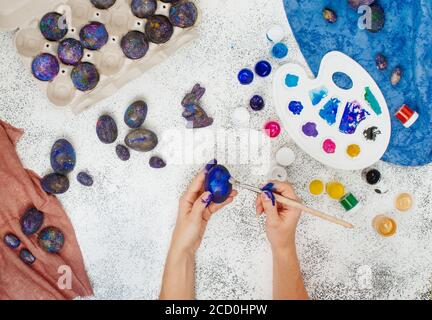 vacunación Profesor de escuela Mente Manos femeninas pintura galaxia huevos de Pascua sobre fondo gris concreto;  vista superior, plano Fotografía de stock - Alamy
