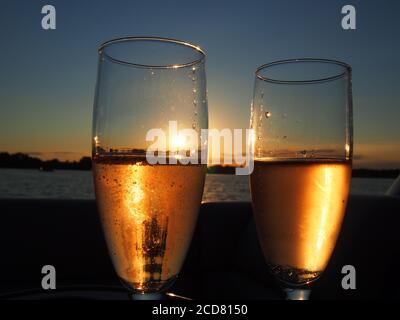 Un par de copas de champán llenas de rosas espumosas puesta de sol