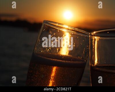 Un par de copas de champán llenas de rosas espumosas puesta de sol