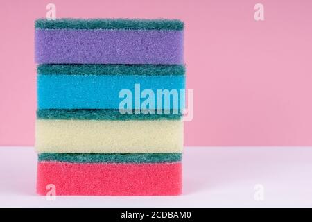 Esponjas multicolores para lavar platos sobre fondo rosa. Concepto de limpieza. Foto de stock