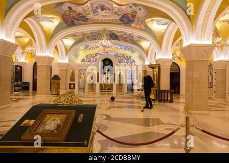 BELGRADO, SERBIA - 24 DE NOVIEMBRE de 2019: La gente vacila el piso detrás de iconos dentro de la cripta del Templo de San Sava, una de las sedes del serbio Foto de stock