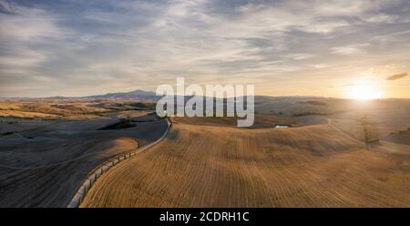 Panorama aéreo de la hermosa puesta de sol sobre las colinas toscanas, granjas, carreteras bordeadas de cipreses