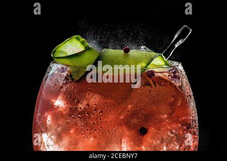primer plano de tónico de ginebra rojo burbujeante con pepino y pimienta Foto de stock