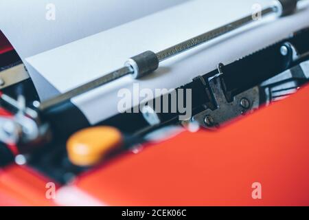 Hoja de papel blanco de primer plano insertada en una máquina de escribir de color rojo brillante