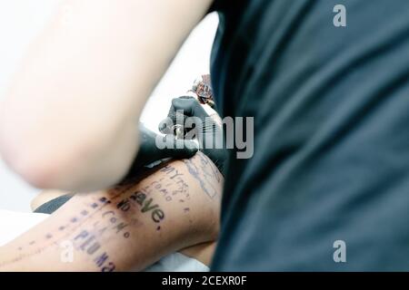 Tatuaje usando máquina y haciendo tatuajes con tinta negra salón en cliente  anónimo recortado Fotografía de stock - Alamy