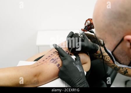Recortar tatuaje masculino con máquina de hacer tatuaje en el