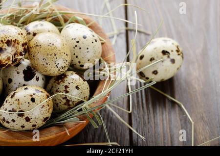Huevos de codorniz orgánicos frescos en cuenco de madera sobre mesa de cocina rústica. Espacio para texto.