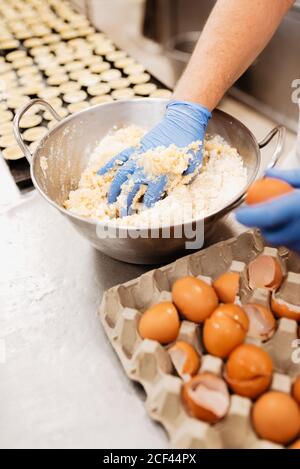 Corte al hombre con uniforme y guantes usando un cuchillo para cortar dulce  pastel fresco en la mesa en la panadería Fotografía de stock - Alamy