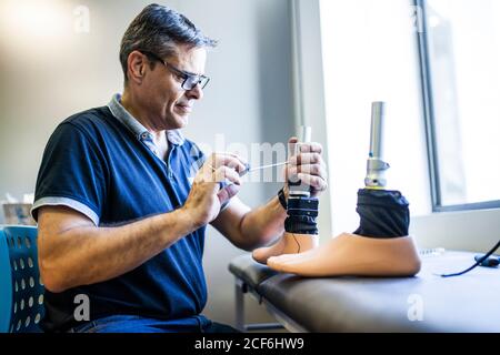 Ingeniero protésico revisando la prótesis de un paciente y mejorando el material en su taller Foto de stock