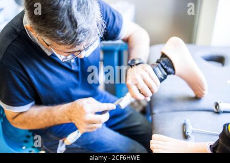 Ingeniero protésico revisando la prótesis de un paciente y mejorando el material en su taller Foto de stock