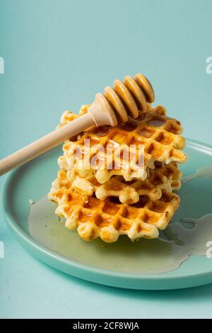 Enfoque selectivo, gofres belgas de azúcar con miel de flores en un plato azul Foto de stock