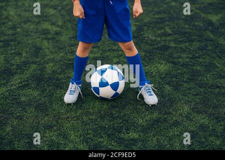 Ángulo alto de niño sin rostro en pantalones cortos y tacos azules con el  balón solo en la cancha verde mientras juegas al fútbol en el estadio  moderno Fotografía de stock - Alamy