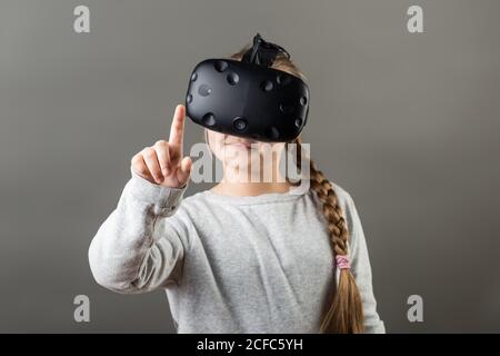 La niña se lleva con el dispositivo VR y el dedo toque aire