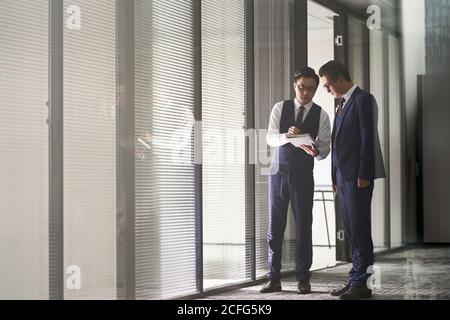 dos ejecutivos corporativos asiáticos que están en el cargo discutiendo negocios
