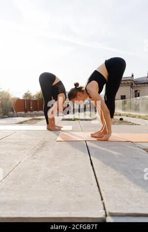 Dos niñas practicar ejercicios de estiramiento y yoga ejercicios juntos en la terraza Foto de stock