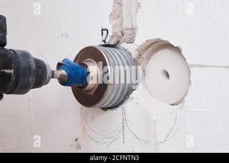 El constructor con perforador de perforación de hummer taladra el agujero en la pared Foto de stock