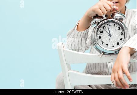 Niño que sostiene la alarma con las 7 en punto en la cara del