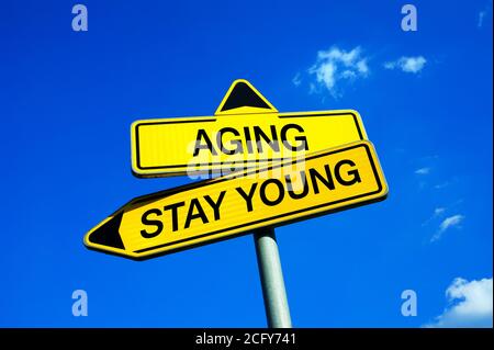 Envejecer o permanecer joven - señal de tráfico con dos opciones - la decisión de mantenerse atractivo y en forma y saludable buen estado físico a pesar de la edad y. Foto de stock