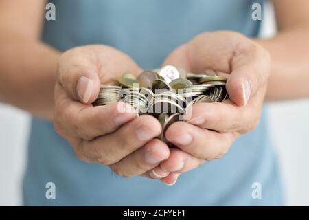 Monedas en dos manos. Concepto de ahorro de dinero. Foto de stock