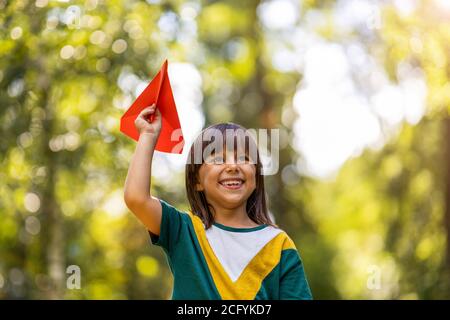 Niña jugando con el avión de papel en el parque Foto de stock