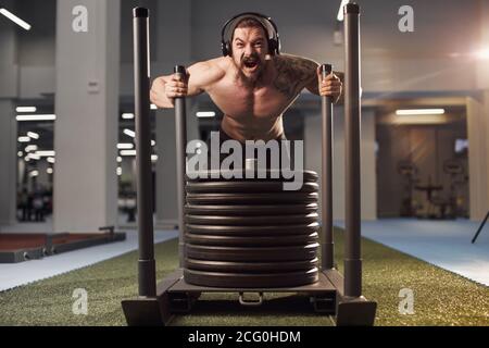 Empujar el trineo de Crossfit hombre empujando pesos ejercicio de  entrenamiento Fotografía de stock - Alamy