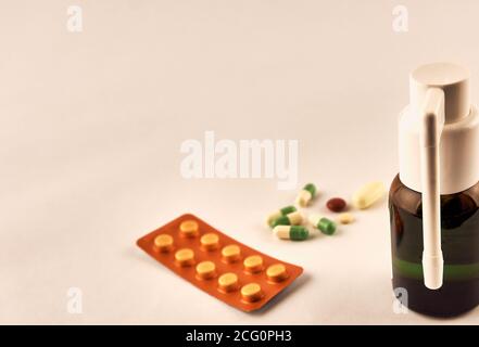 Un grupo de pastillas y cápsulas variadas junto a una ampolla y un aerosol. Foto de stock