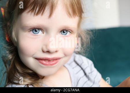 Retrato de niña con ojos azules y una sonrisa leve Foto de stock
