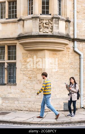 Mujer turista asiática que sigue leyendo una guía en Catte Street en Oxford Oxfordshire mientras la gente local pasa