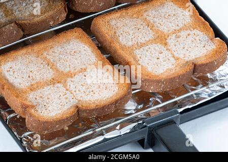 Tiro horizontal de una bandeja tostadora con cuatro pedazos de pan de trigo  con mantequilla entrando en una tostadora Fotografía de stock - Alamy