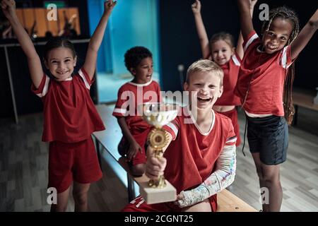 El equipo de fútbol infantil en un vestuario celebrando el triunfo