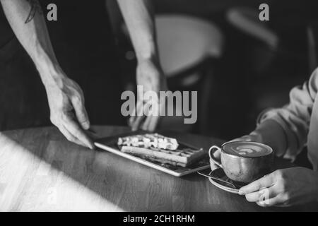foto en blanco y negro. pedido listo. un camarero está trayendo la orden de la mujer