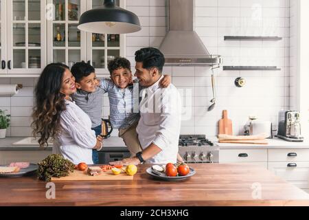 Familia abrazando y jugando unos con otros en la cocina divertida tiempo