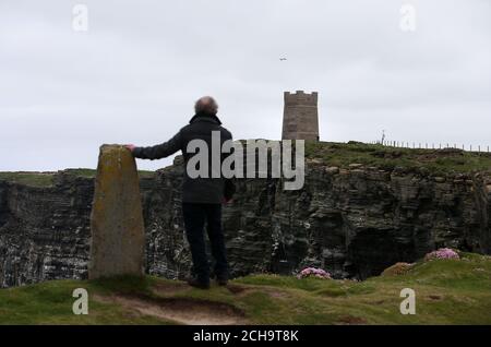 Los visitantes caminan a lo largo de las cimas del acantilado sobre el mar en Marwick Head en Orkney, donde se alza la torre construida para honrar la memoria de Lord Kitchener.