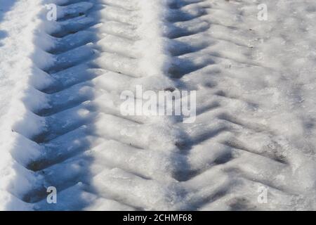 Deep pistas de los neumáticos de un grande, posiblemente, carro o tractor de carga sobre el blanco de la nieve en el invierno, off road Foto de stock