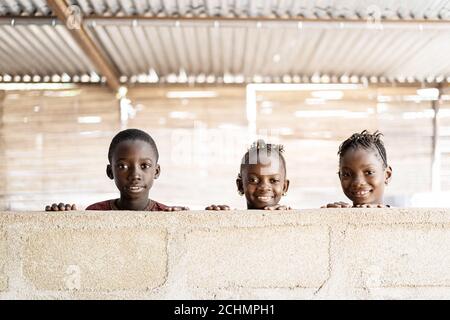 Tres niños negros africanos maravillosos jugando, sonriendo y riendo detrás de Wall