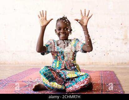 African Fun Party Girl, mujer sonriente lanzando confeti, contra un fondo blanco con Copy Space