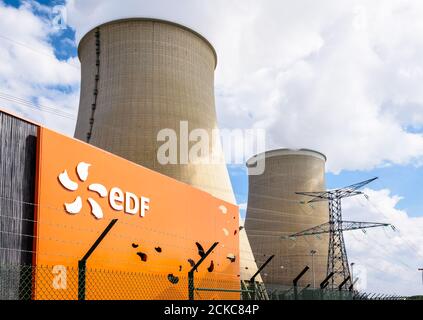 Vista en ángulo bajo del cartel de EDF en la entrada de la central nuclear de Nogent-sur-Seine, Francia, y las dos torres de refrigeración. Foto de stock