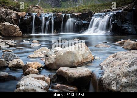 Fairy piscinas cascadas rodeadas de montañas durante un día nublado en la Isla de Skye en Escocia
