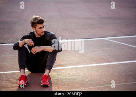 Inesperado Departamento Decorativo Runner vistiendo ropa negra y zapatos rojos descansando sobre la pista de  carreras en stadium Fotografía de stock - Alamy
