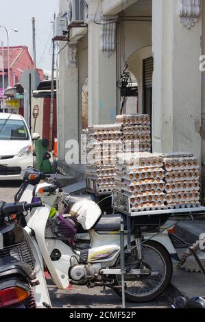 GEORGETOWN, PENANG, MALASIA - 18 de abril de 2016: De huevo de pollo empacado en una scooter esperando al cliente cerca de una pequeña cafetería. Fresco Foto de stock