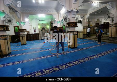Los voluntarios que usan mascarillas pulverizan desinfectante dentro de una mezquita, ya que está preparada para la oración después de ser reabierta, después del brote de la enfermedad coronavirus (COVID-19), en el Cairo, Egipto, 26 de junio de 2020. REUTERS/Mohamed Abd el Ghany