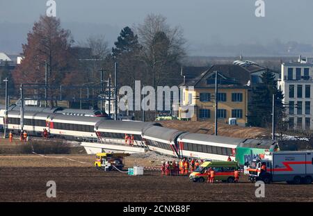 Rescue workers stand next to a derailed train after two trains collided near Rafz around 30 km (18 miles) from Zurich February 20, 2015. Two passenger trains collided in Switzerland on Friday, causing five injuries and disrupting commuter routes into Zurich, police and rail operator SBB said. REUTERS/Arnd Wiegmann (SWITZERLAND - Tags: DISASTER TRAVEL TRANSPORT TPX IMAGES OF THE DAY)